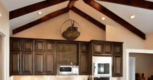Kitchen with wooden beams and ceiling fan, featuring vaulted ceiling and cabinets.